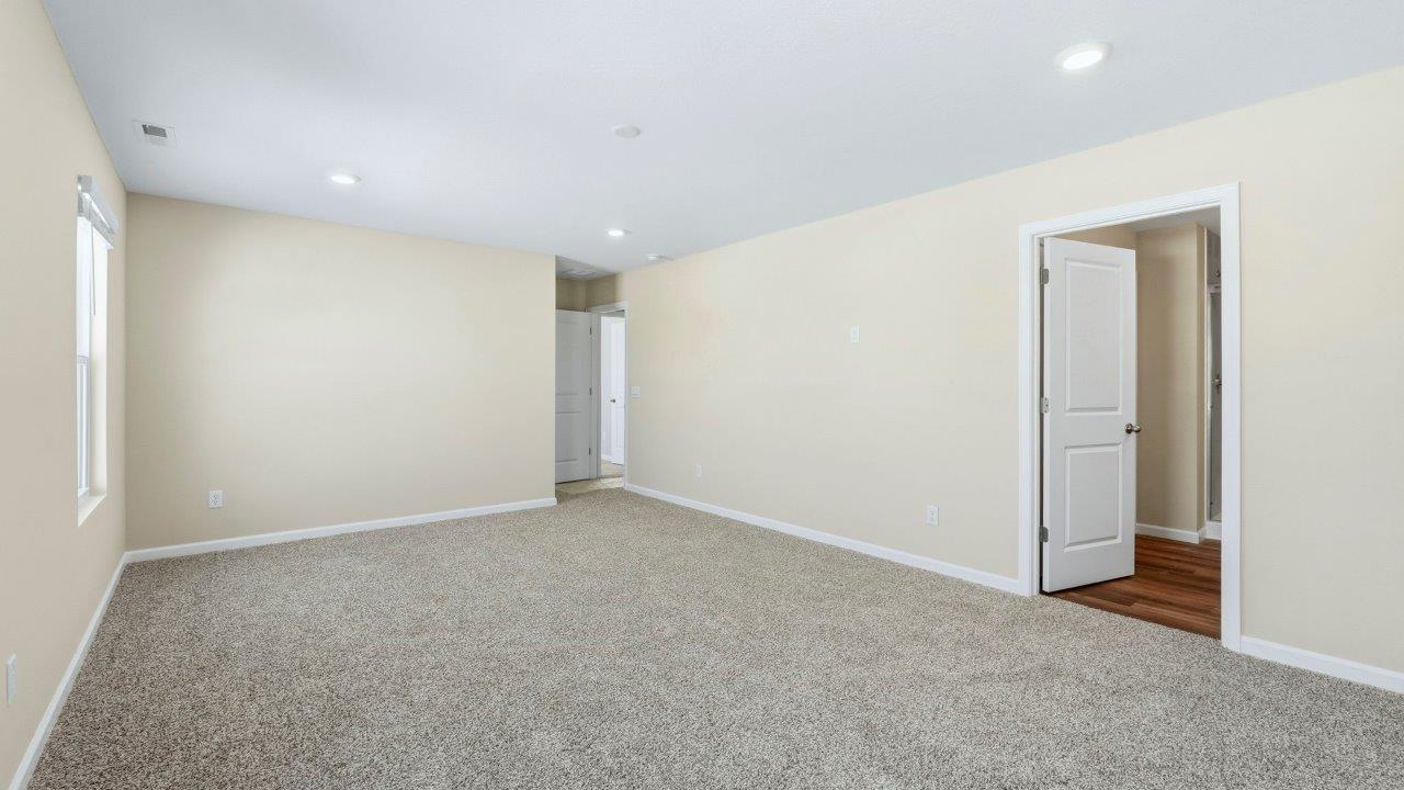 primary bedroom with elk beige carpet flooring, 2 windows, and ensuite bath and closet
