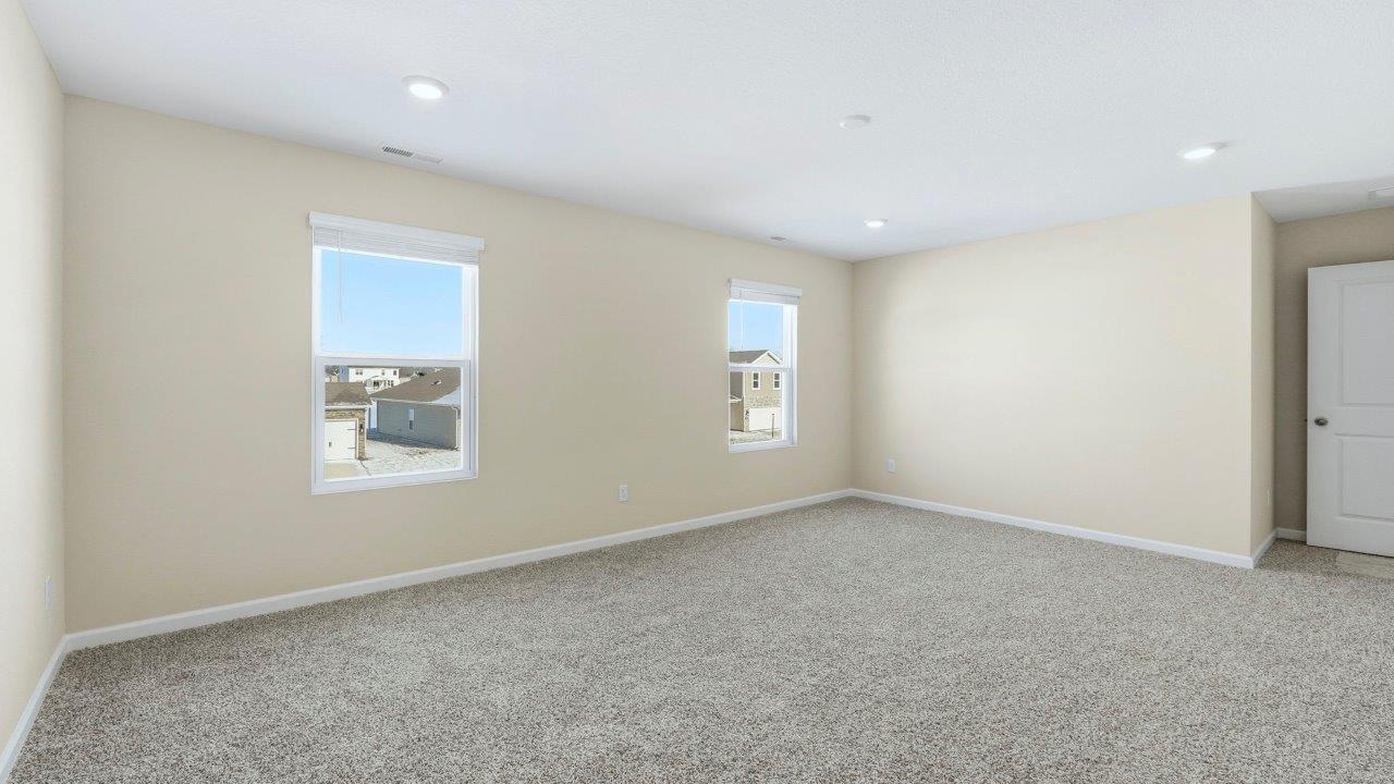 primary bedroom with elk beige carpet flooring, 2 windows, and ensuite bath and closet