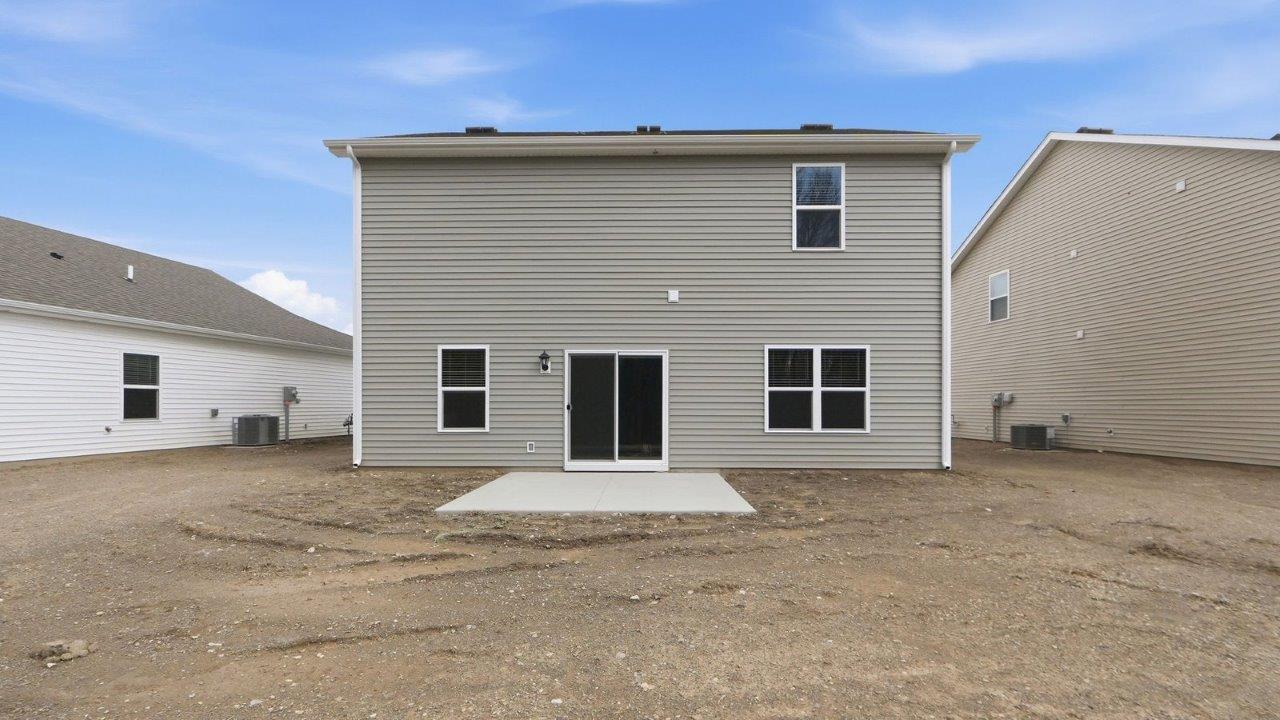 rear exterior with concrete patio and tree lined yard