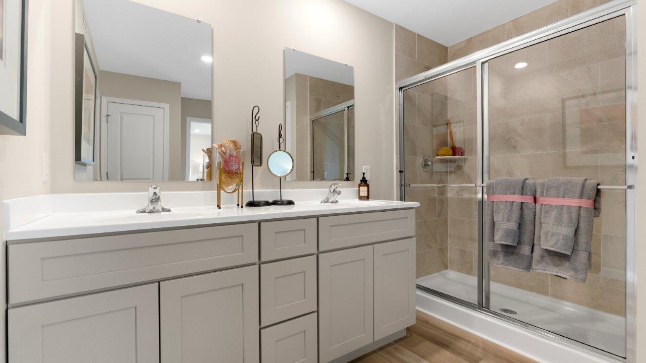 Henley primary bath with dual sinks, lvp, and ceramic tile walk in shower
