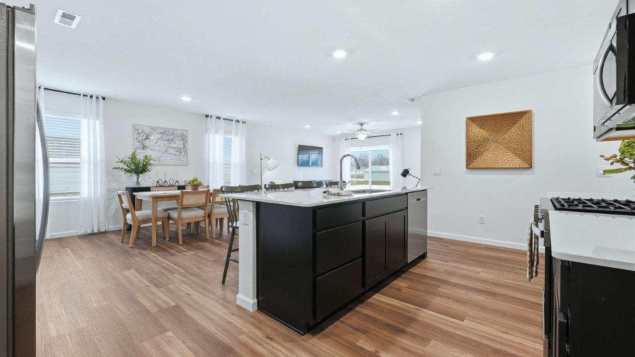 thunderhawk model home elm plan kitchen with sarsaparilla shaker cabinets, quartz countertops, center island with bar seating, pantry, and stainless steel appliances