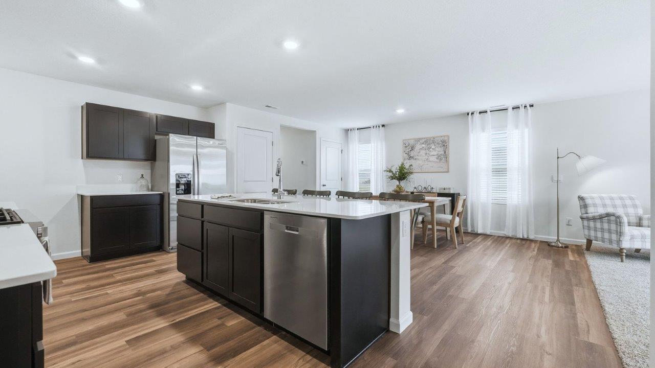 thunderhawk model home elm plan kitchen with sarsaparilla shaker cabinets, quartz countertops, center island with bar seating, pantry, and stainless steel appliances