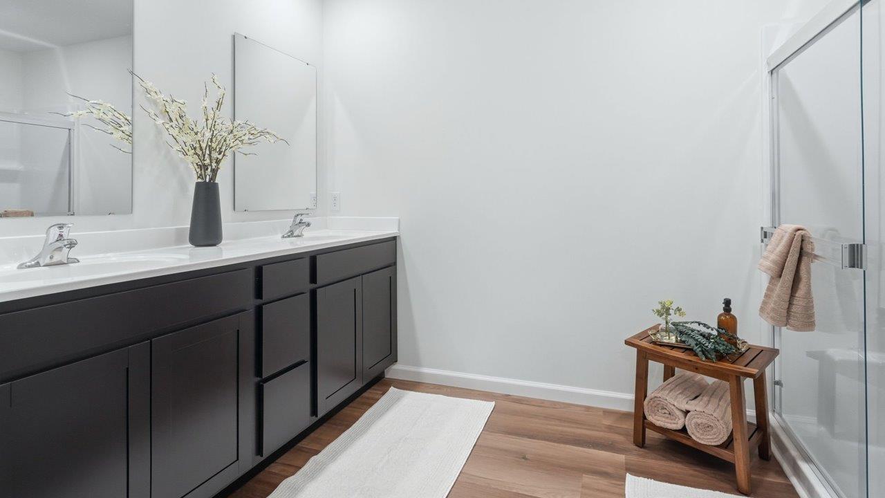 thunderhawk elm model home primary ensuite bathroom with dual vanity sink mohawk lvp flooring and walk in shower