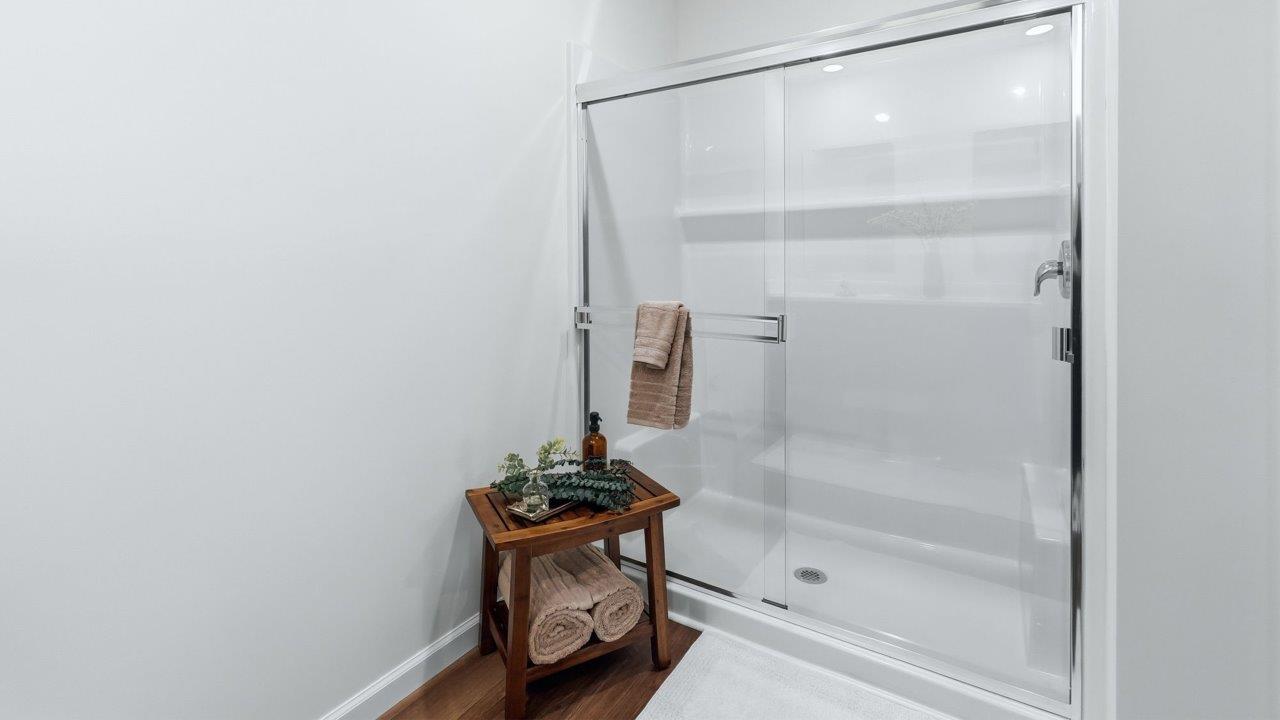 thunderhawk elm model home primary ensuite bathroom with dual vanity sink mohawk lvp flooring and walk in shower