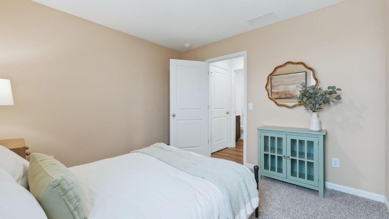 thunderhawk model home elm plan first floor guest bedroom with single window, beige carpet, light brown walls, and closet