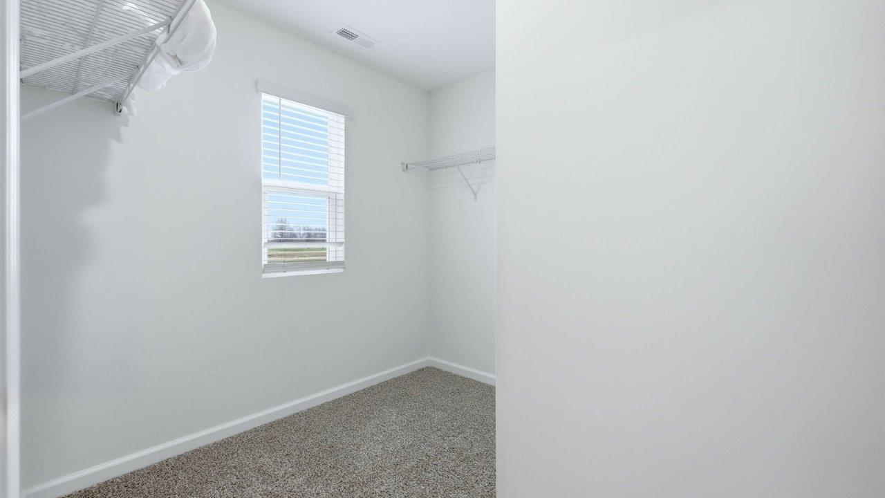 thunderhawk model home elm plan primary ensuite walk-in closet with built-in shelving, white walls, and built-in shelf