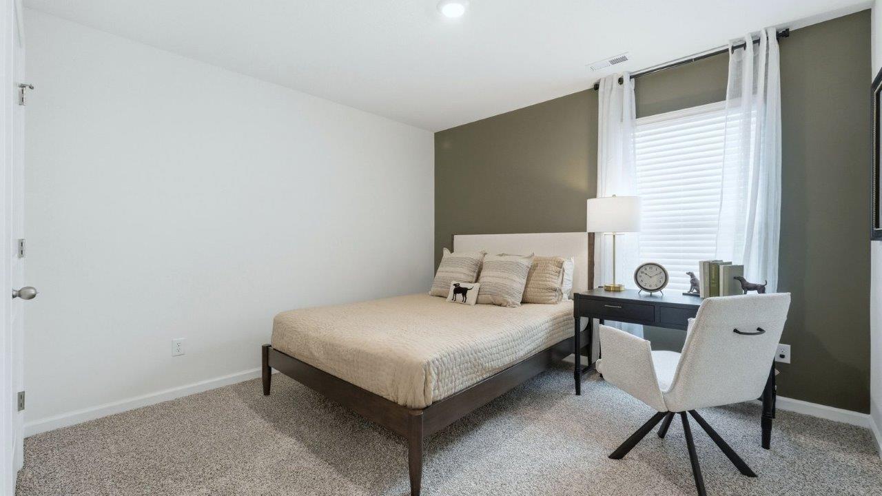 thunderhawk model home elm plan bedroom 2 with beige carpet, white and green walls, closet, and 1 window