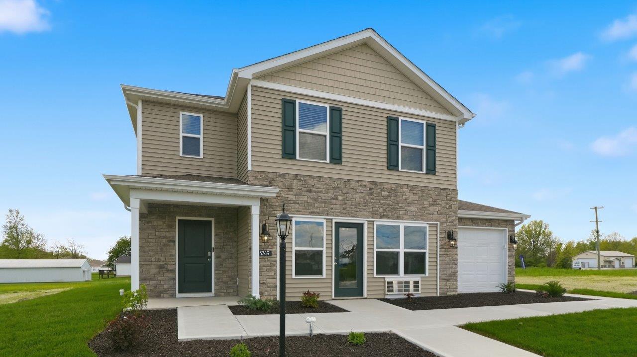 Thunderhawk elm model home exterior with ridgeline stone, sod, landscaping, and a 3 car garage