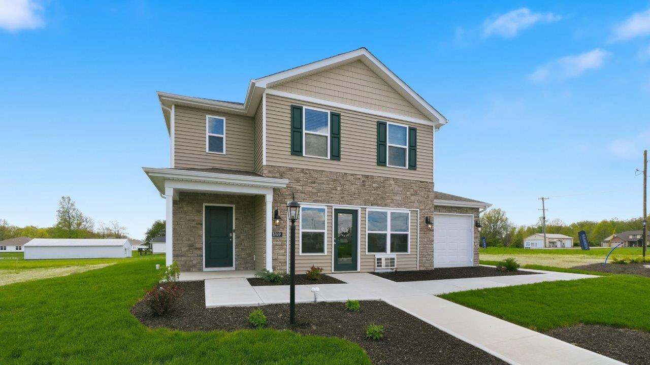 Thunderhawk elm model home exterior with ridgeline stone, sod, landscaping, and a 3 car garage