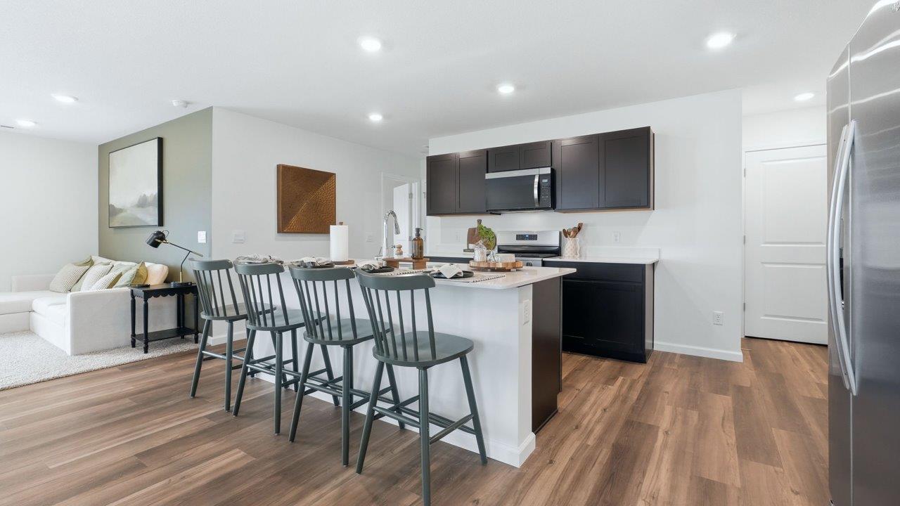 thunderhawk elm model home kitchen with sarsaparilla cabinets, quartz countertops, pantry, and spacious center island with bar seating