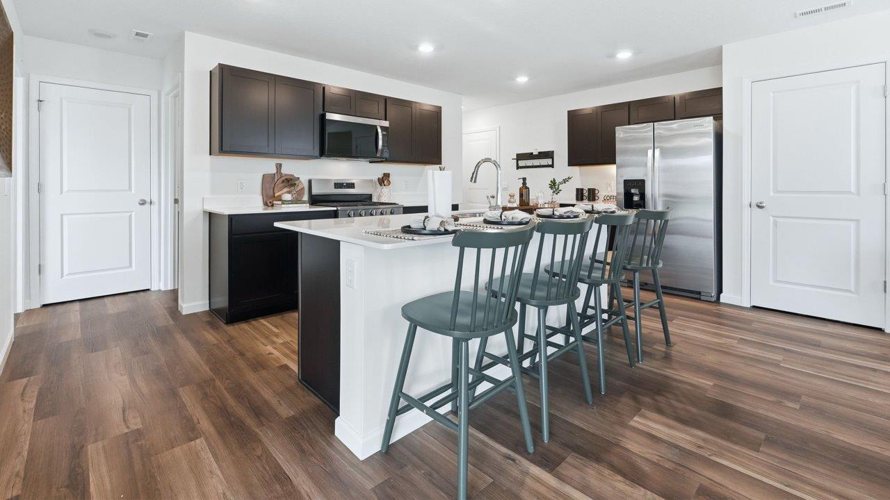 thunderhawk elm model home kitchen with sarsaparilla cabinets, quartz countertops, pantry, and spacious center island with bar seating