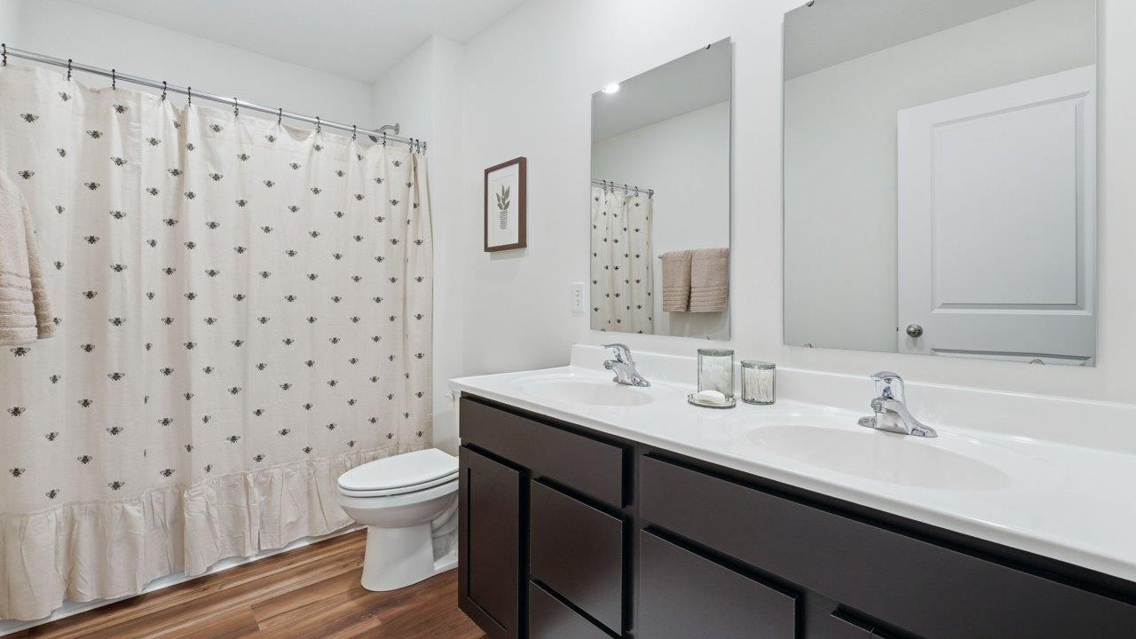 thunderhawk elm full bathroom with dual sink vanity, tub shower, and lvp flooring
