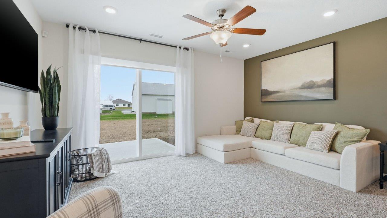 thunderhawk elm living room with biege carpet, white and green walls, ceiling fan, and sliding glass door to backyard patio