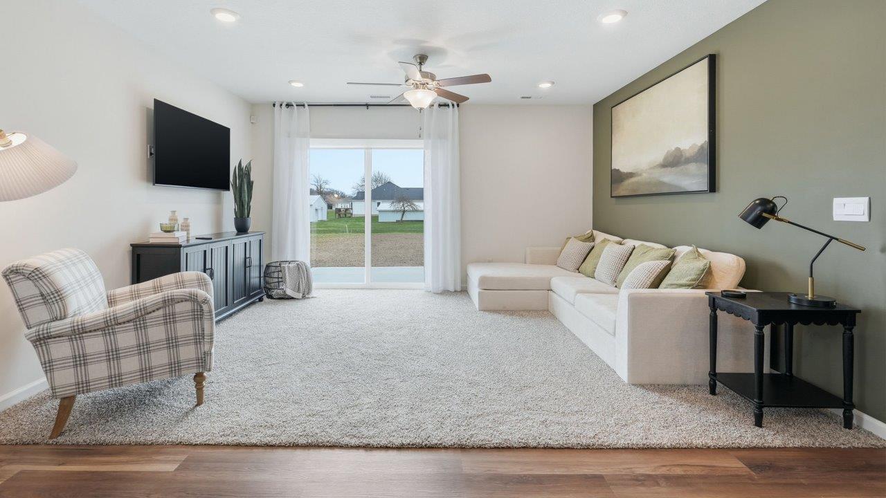 thunderhawk elm living room with biege carpet, white and green walls, ceiling fan, and sliding glass door to backyard patio