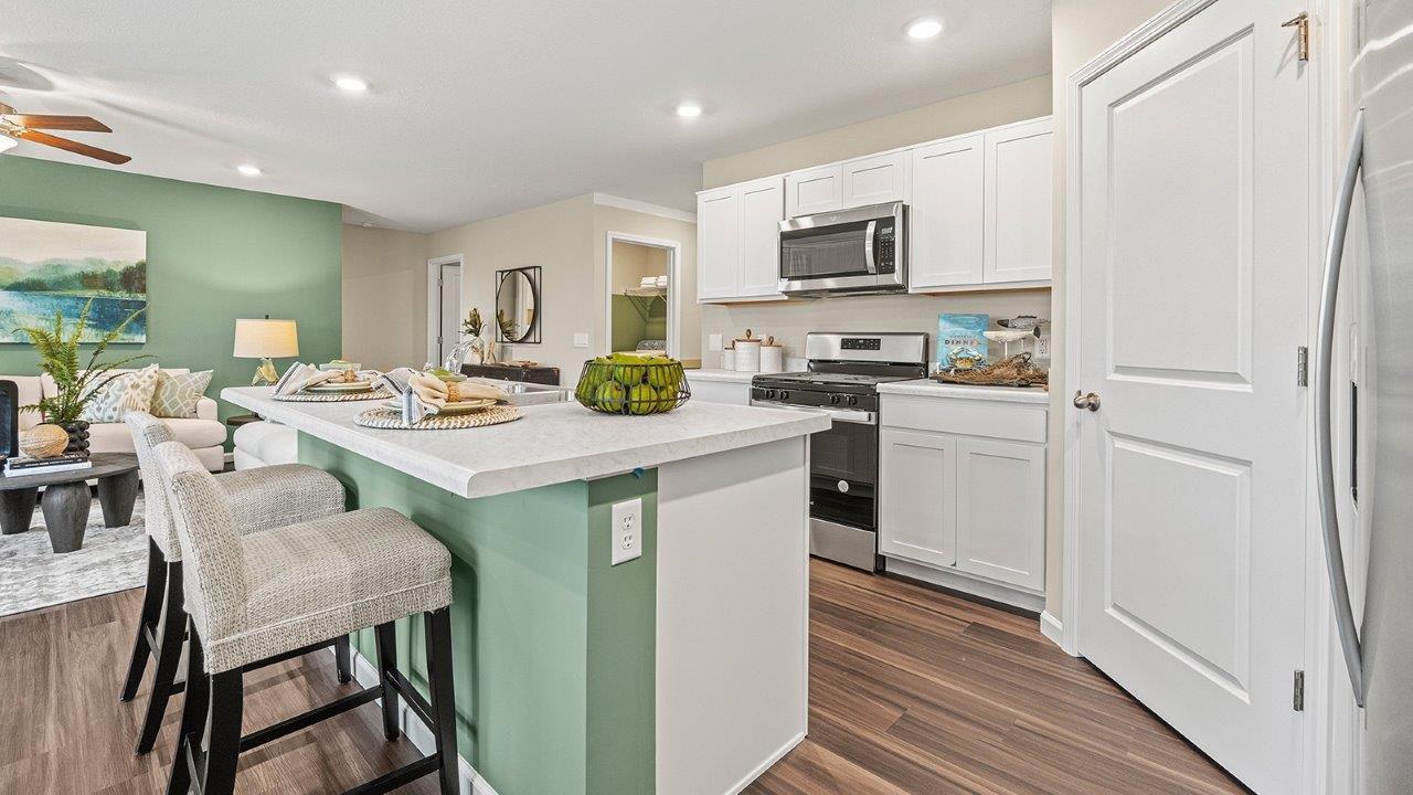 harmony kitchen with white cabinets, stainless steel appliances, corner pantry, and center island with bar seating