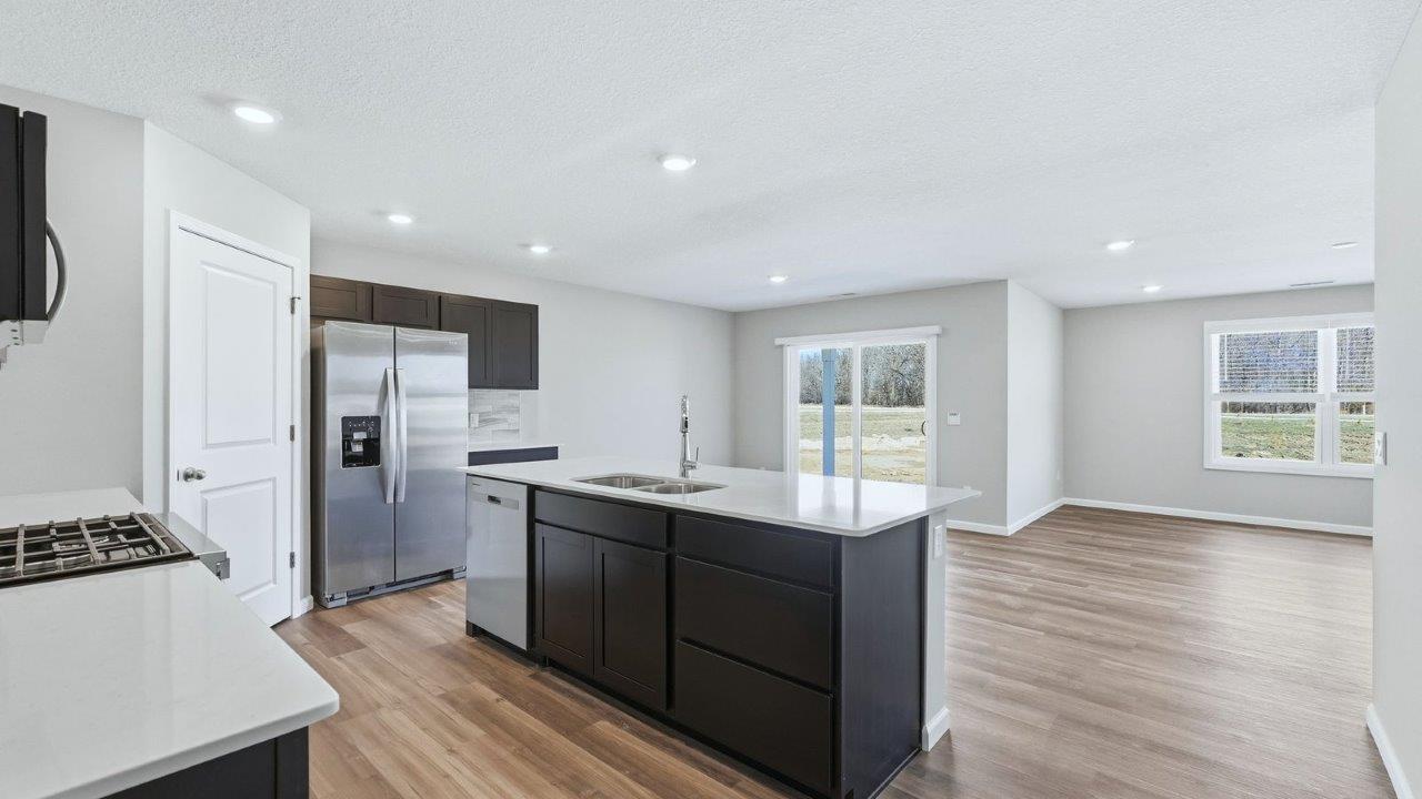 kitchen with sarsaparilla cabinets, lvp, quartz counters, corner pantry, stainless steel appliances, and center island with bar seating