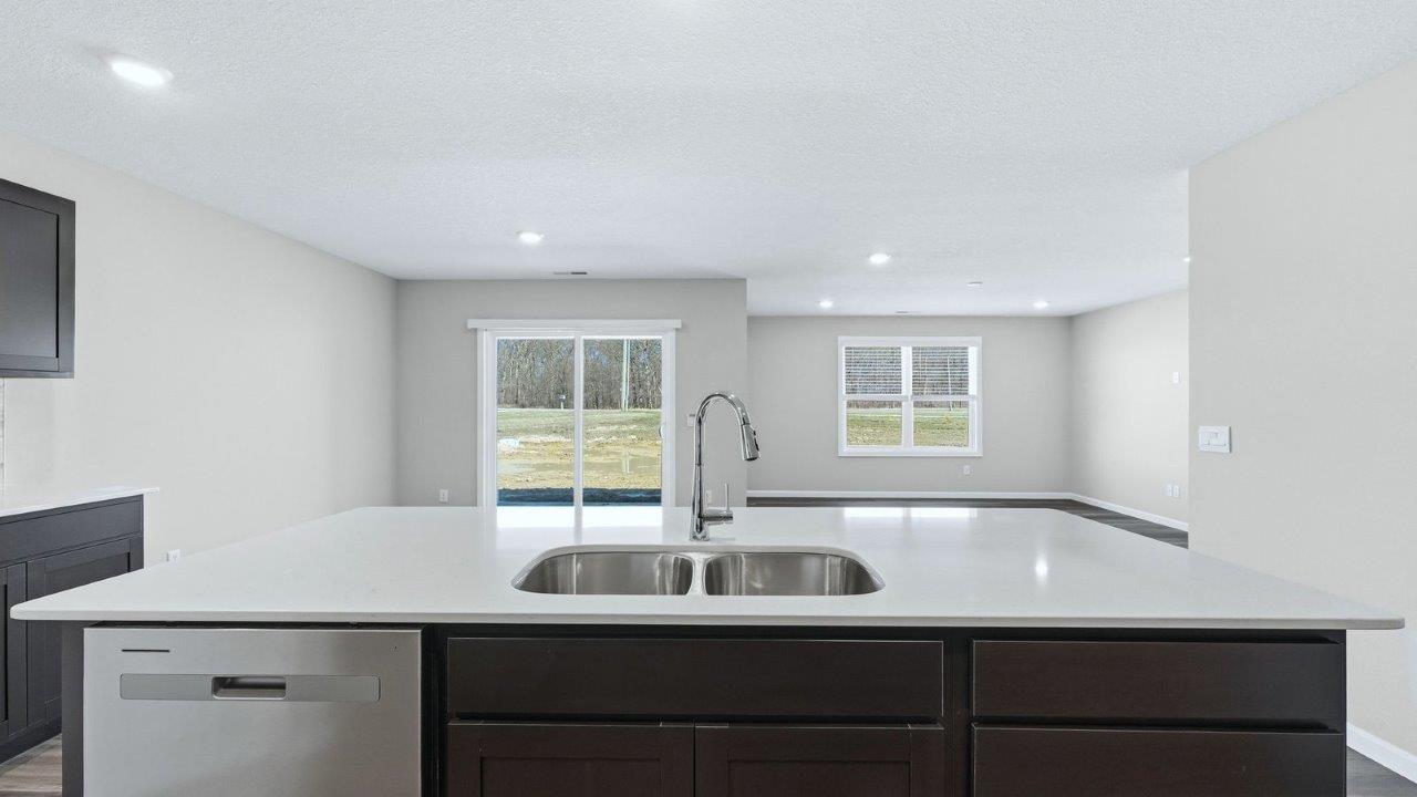 kitchen with sarsaparilla cabinets, lvp, quartz counters, corner pantry, stainless steel appliances, and center island with bar seating