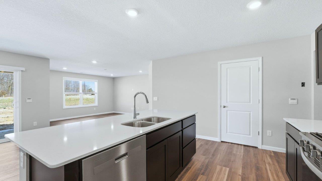 kitchen with sarsaparilla cabinets, lvp, quartz counters, corner pantry, stainless steel appliances, and center island with bar seating