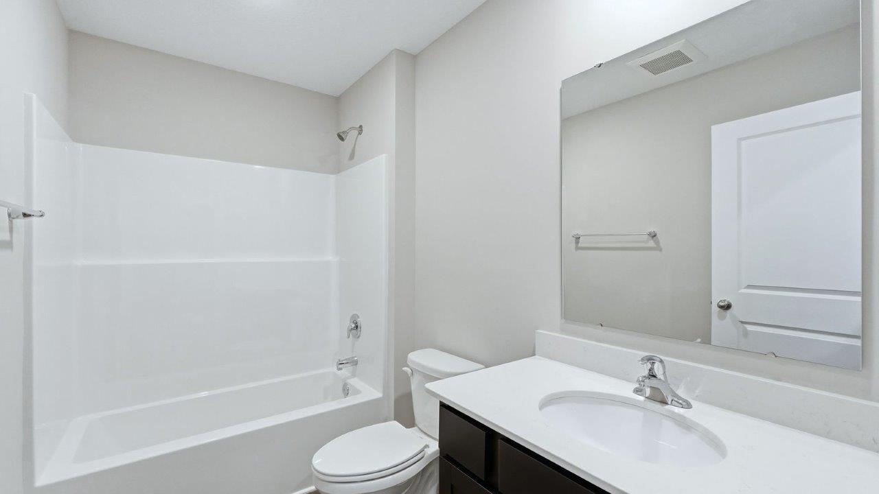 full bathroom with single sink vanity, lvp, and fiberglass tub shower