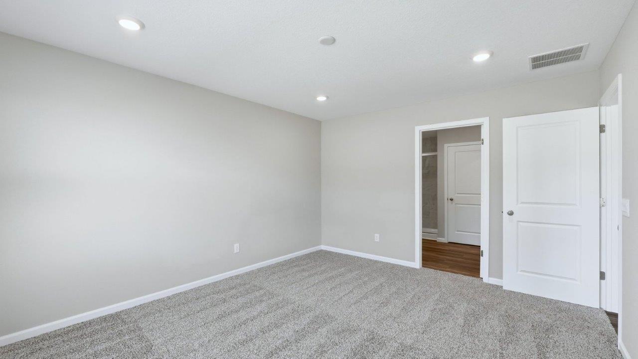 primary bedroom with beige carpet, popular grey walls, and ensuite bathroom and closet