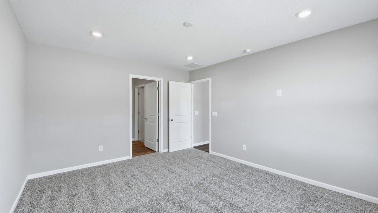 primary bedroom with beige carpet, popular grey walls, and ensuite bathroom and closet