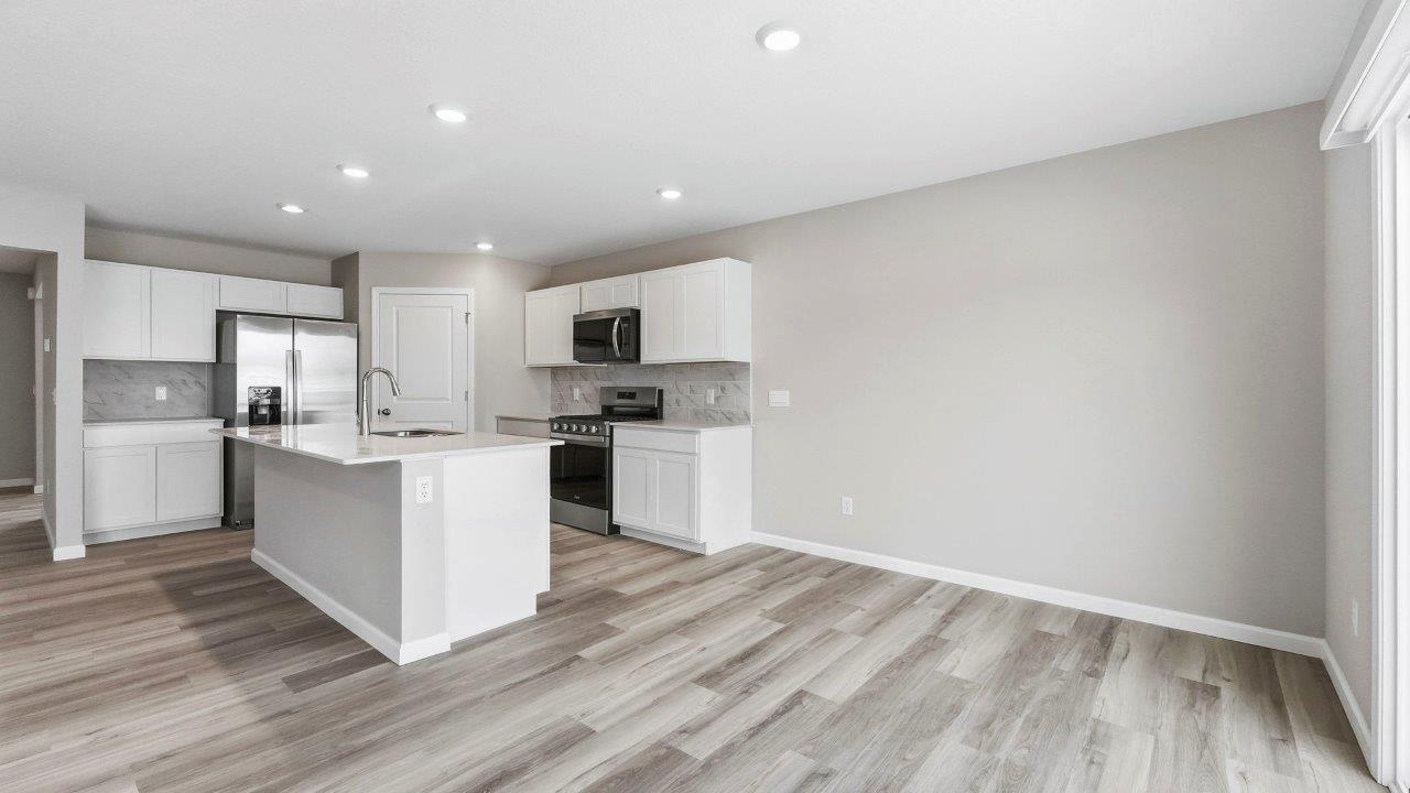 kitchen with white cabinets, corner pantry, quartz counters, center island, and stainless steel appliances