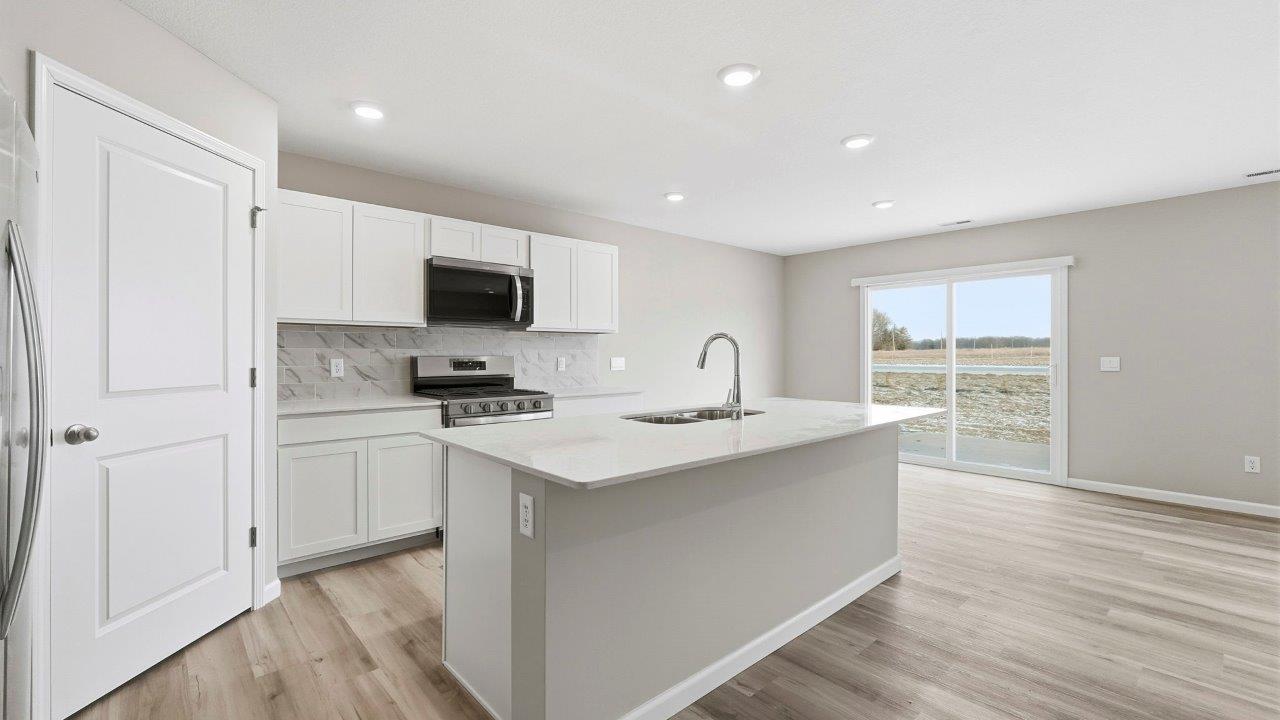 kitchen with white cabinets, corner pantry, quartz counters, center island, and stainless steel appliances