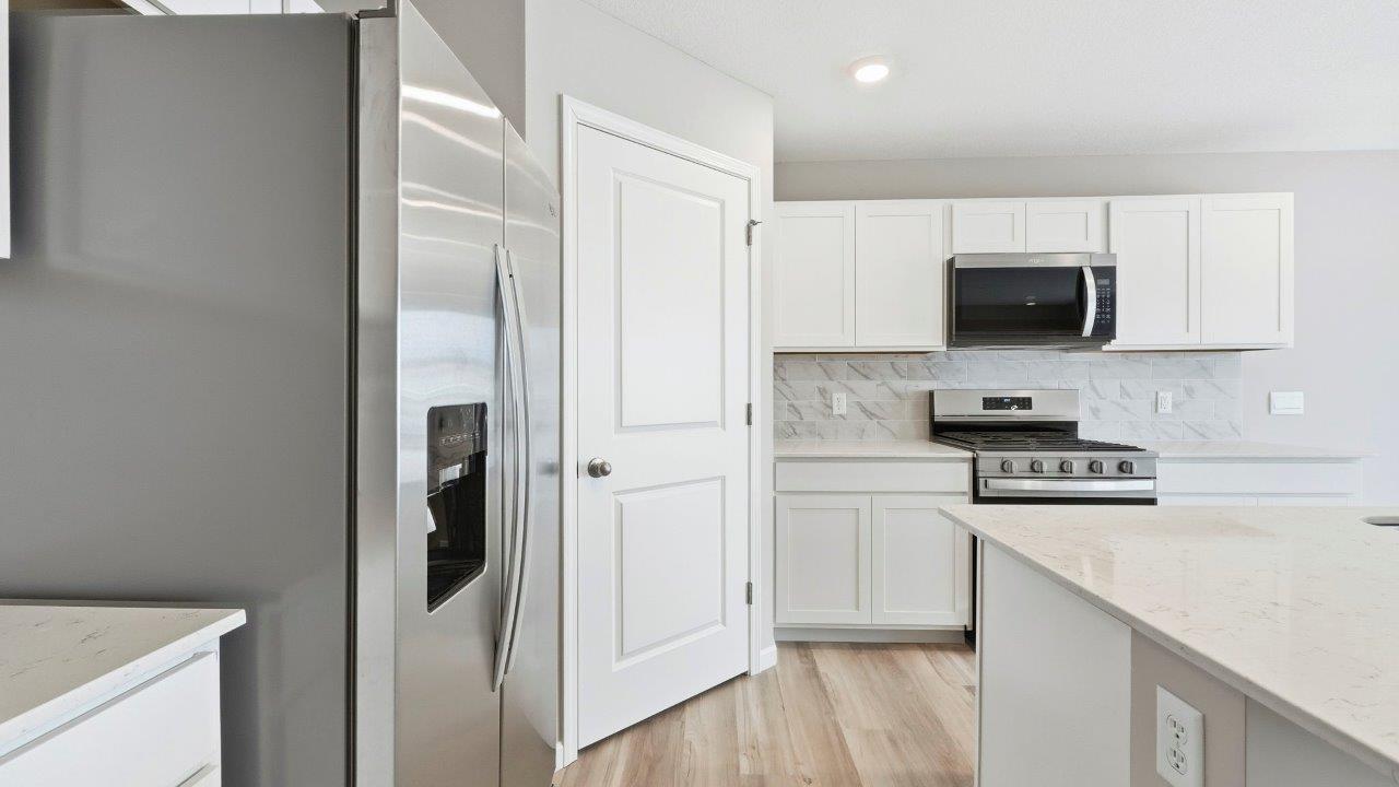 kitchen with white cabinets, corner pantry, quartz counters, center island, and stainless steel appliances