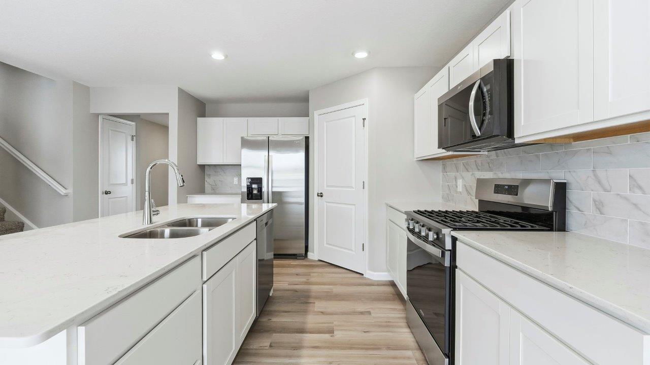 kitchen with white cabinets, corner pantry, quartz counters, center island, and stainless steel appliances