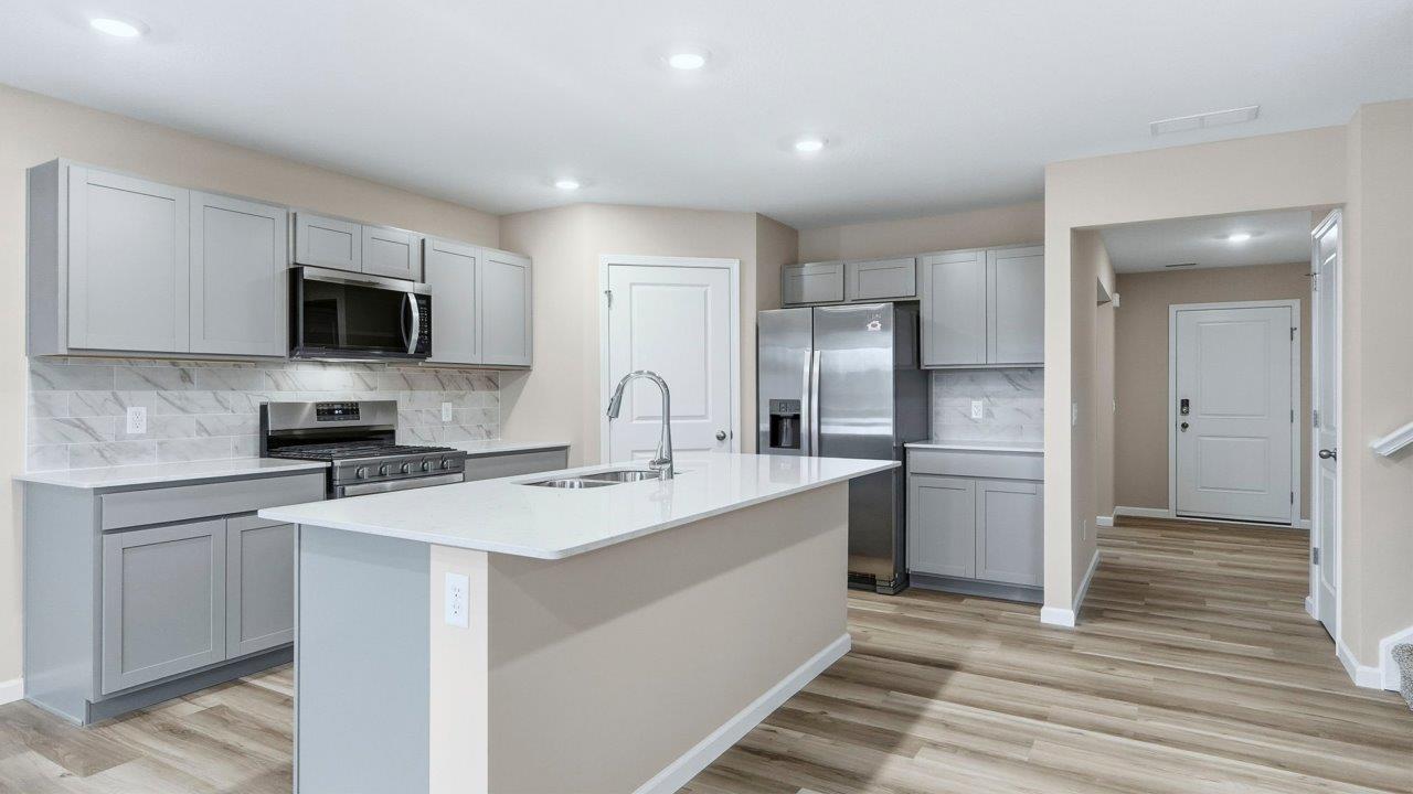 kitchen with grey cabinets, appliances, center island, and corner pantry