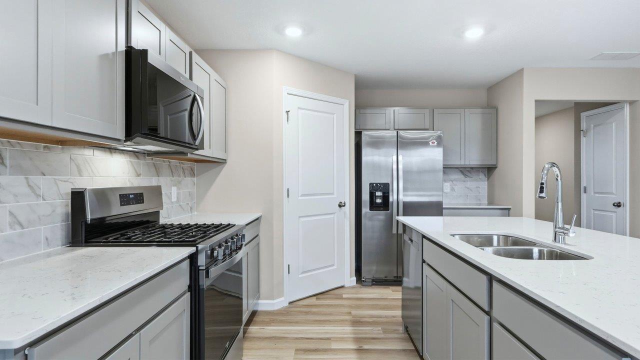 kitchen with grey cabinets, appliances, center island, and corner pantry