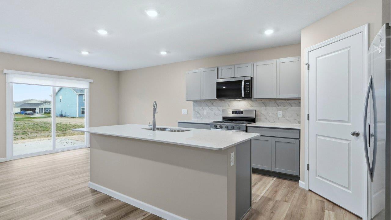 kitchen with grey cabinets, appliances, center island, and corner pantry