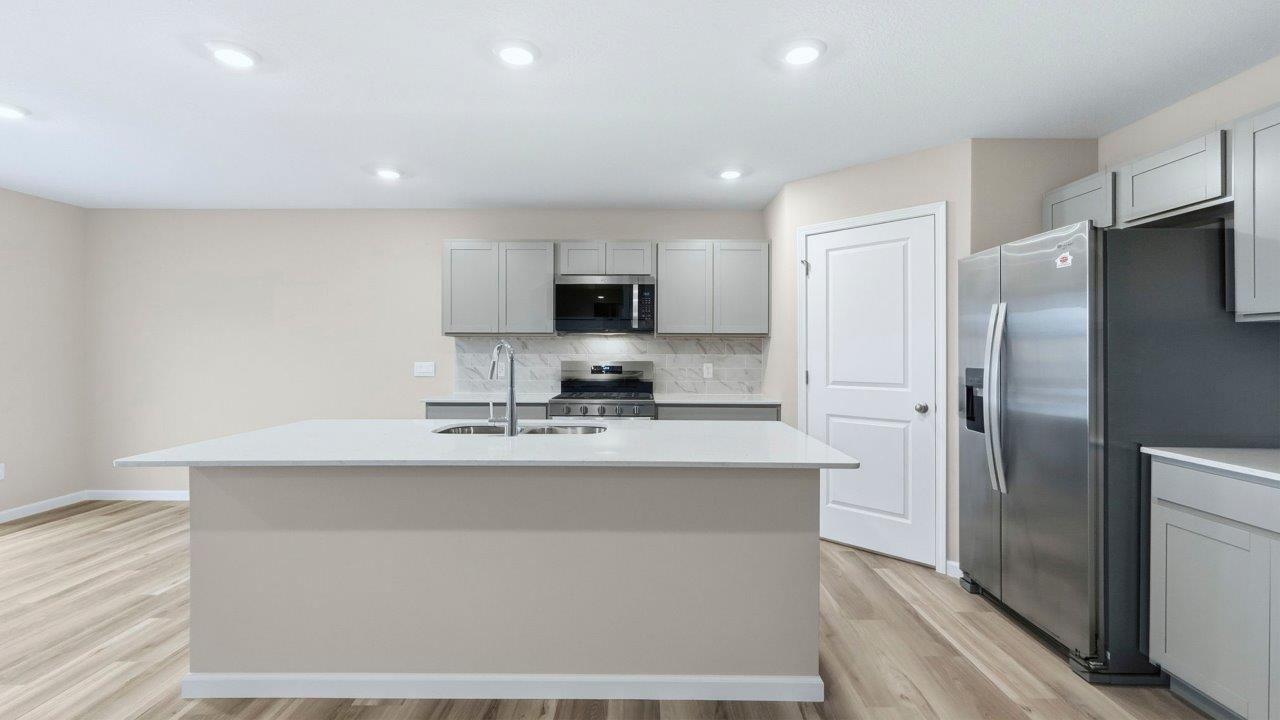 kitchen with grey cabinets, appliances, center island, and corner pantry