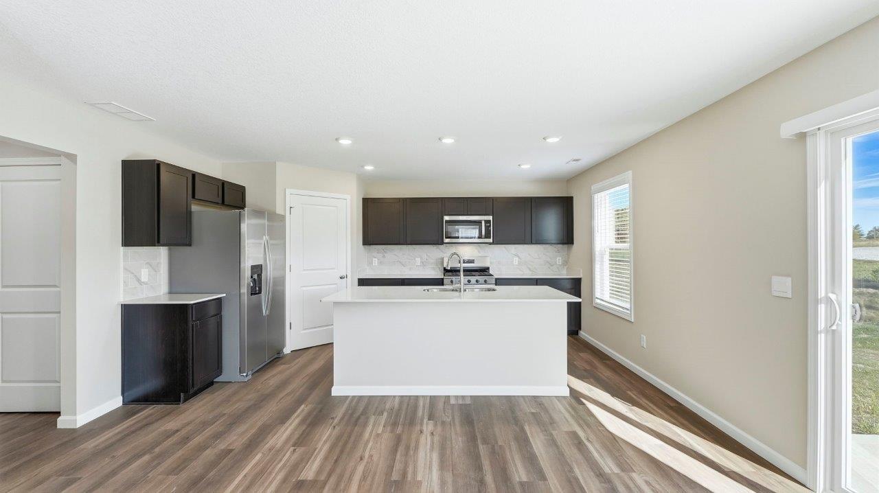 kitchen with sarsaparilla cabinets, stainless steel appliances, corner pantry, and center island with quartz counters