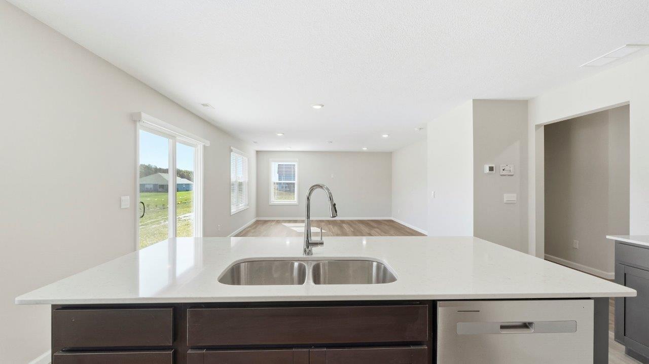 kitchen with sarsaparilla cabinets, stainless steel appliances, corner pantry, and center island with quartz counters