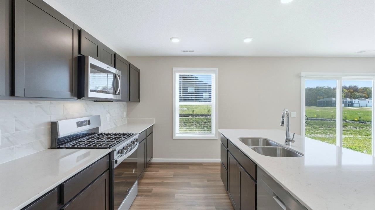 kitchen with sarsaparilla cabinets, stainless steel appliances, corner pantry, and center island with quartz counters