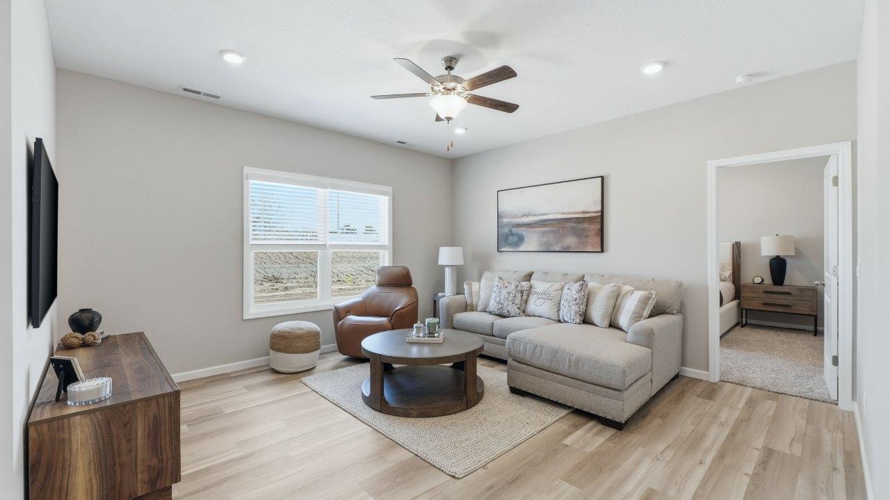 sierra ridge chatham model living room with lvp flooring, ceiling fan, and open layout