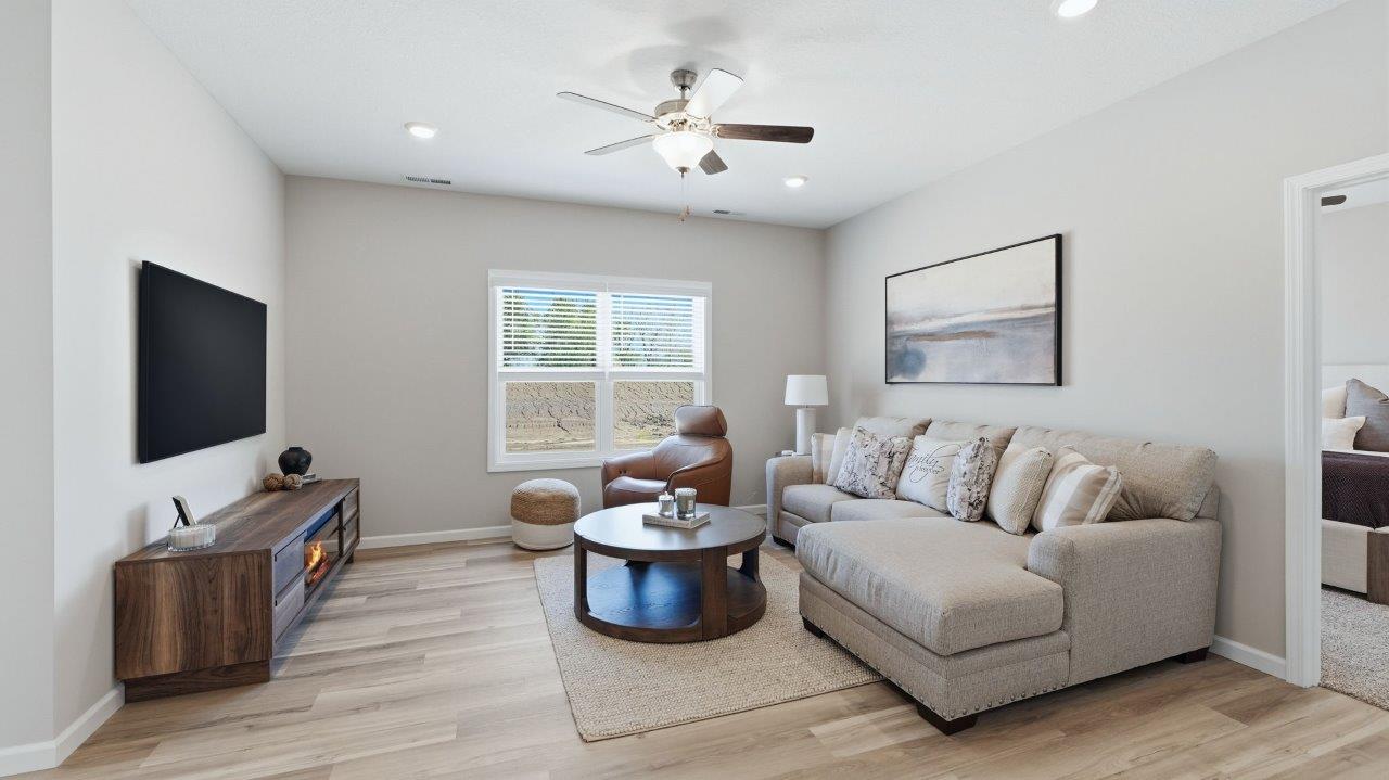 sierra ridge chatham model living room with lvp flooring, ceiling fan, and open layout