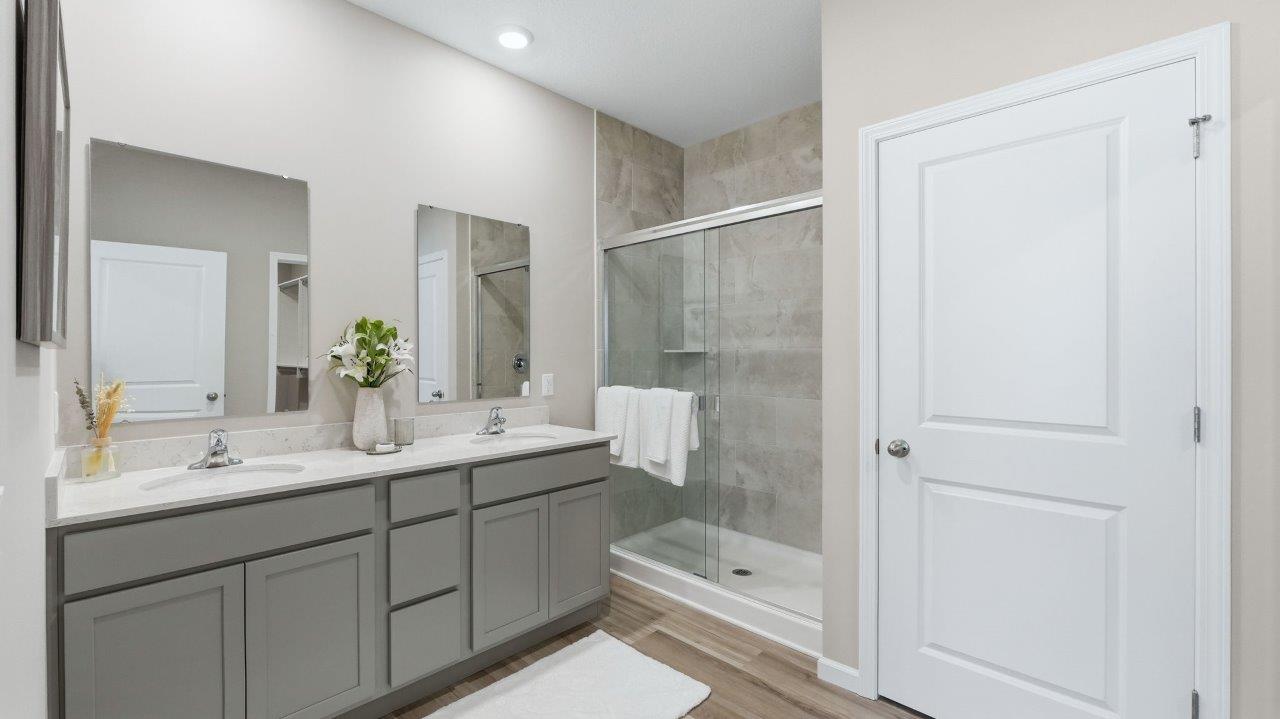 sierra ridge chatham primary bedroom ensuite bathroom with dual sinks, walk in shower, and private toilet room