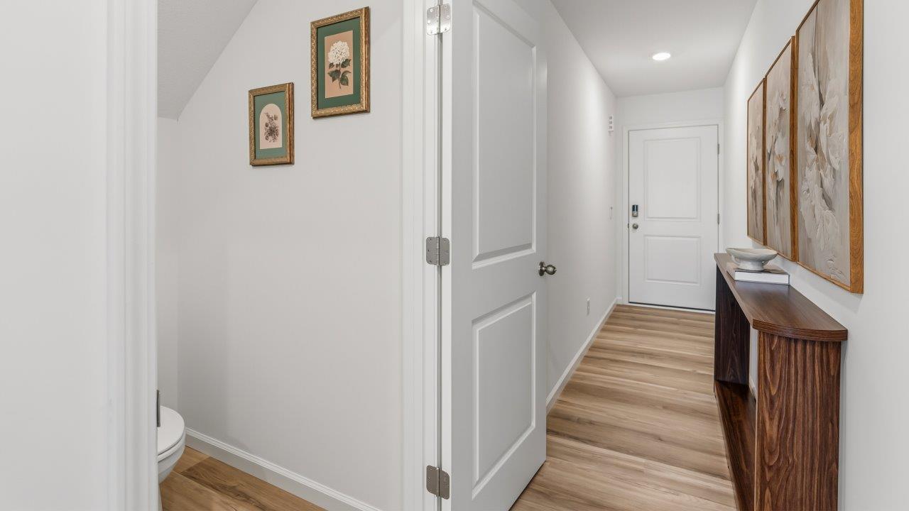 Whispering Pines Pattison Model - front door and foyer with lvp flooring, white walls, and leads into living room