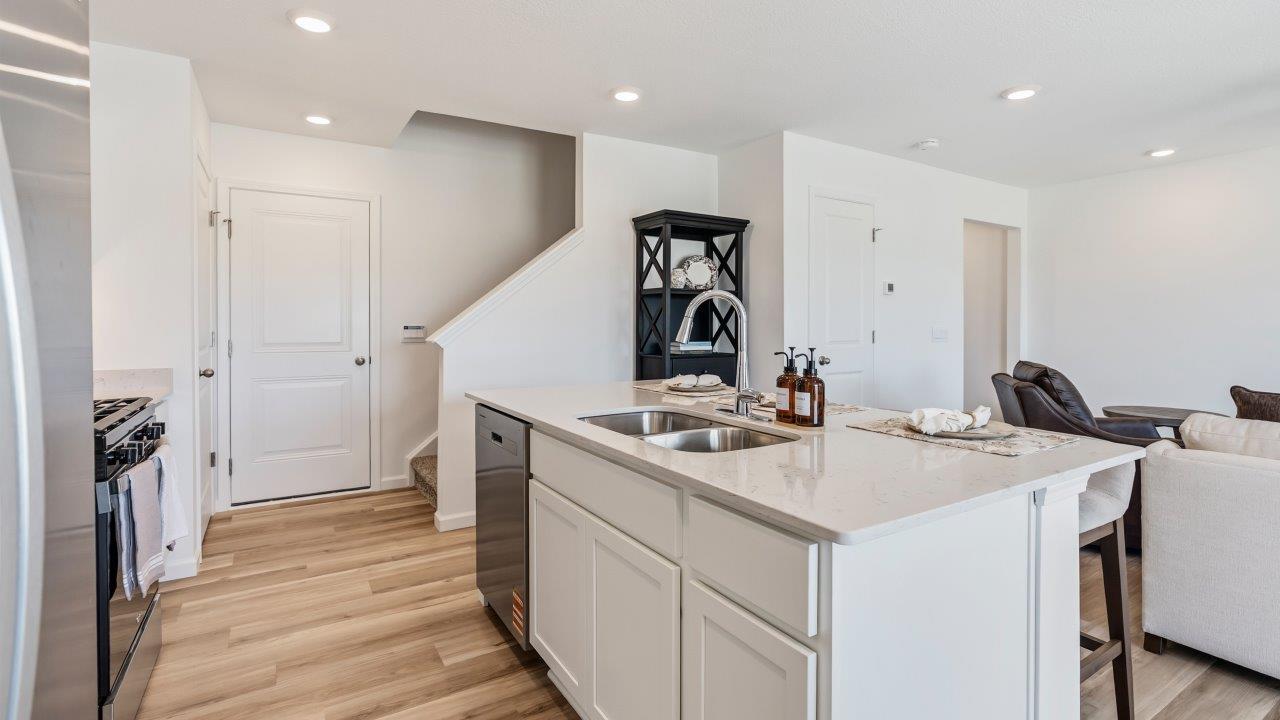 Whispering Pines Pattison Model - kitchen with white cabinets, quartz countertops, center island with bar seating, stainless steel appliances, and pantry