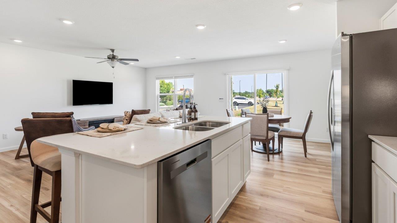 Whispering Pines Pattison Model - kitchen with white cabinets, quartz countertops, center island with bar seating, stainless steel appliances, and pantry