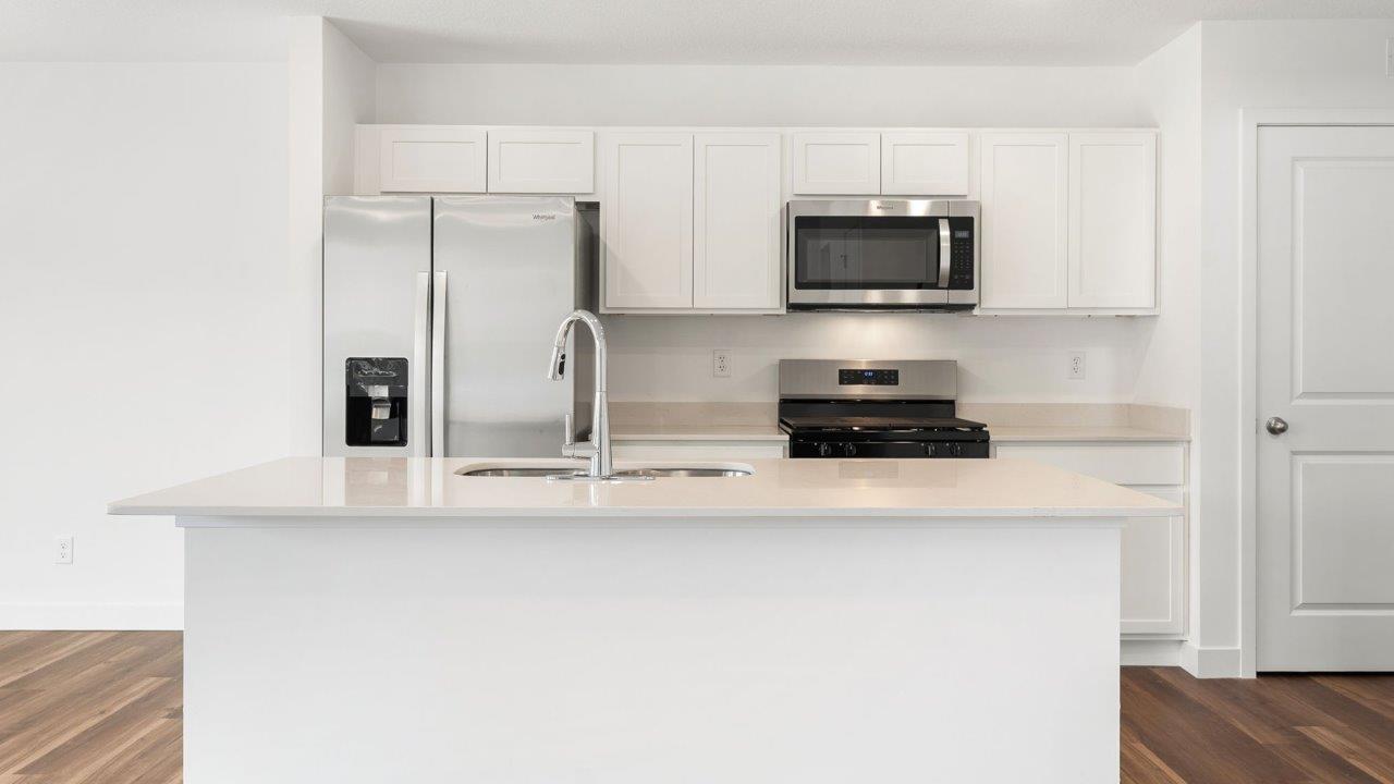 whispering pines portsmouth - kitchen with white cabinets, stainless steel appliances, quartz countertops, center island, and pantry