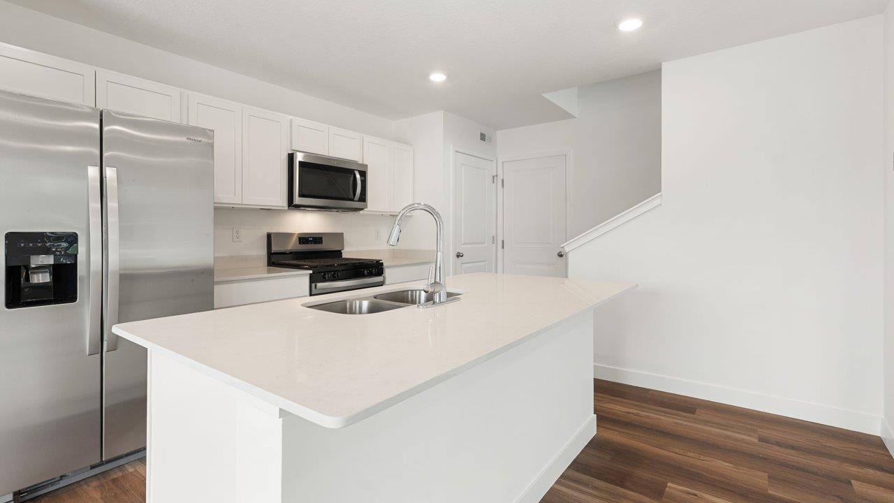 whispering pines portsmouth - kitchen with white cabinets, stainless steel appliances, quartz countertops, center island, and pantry
