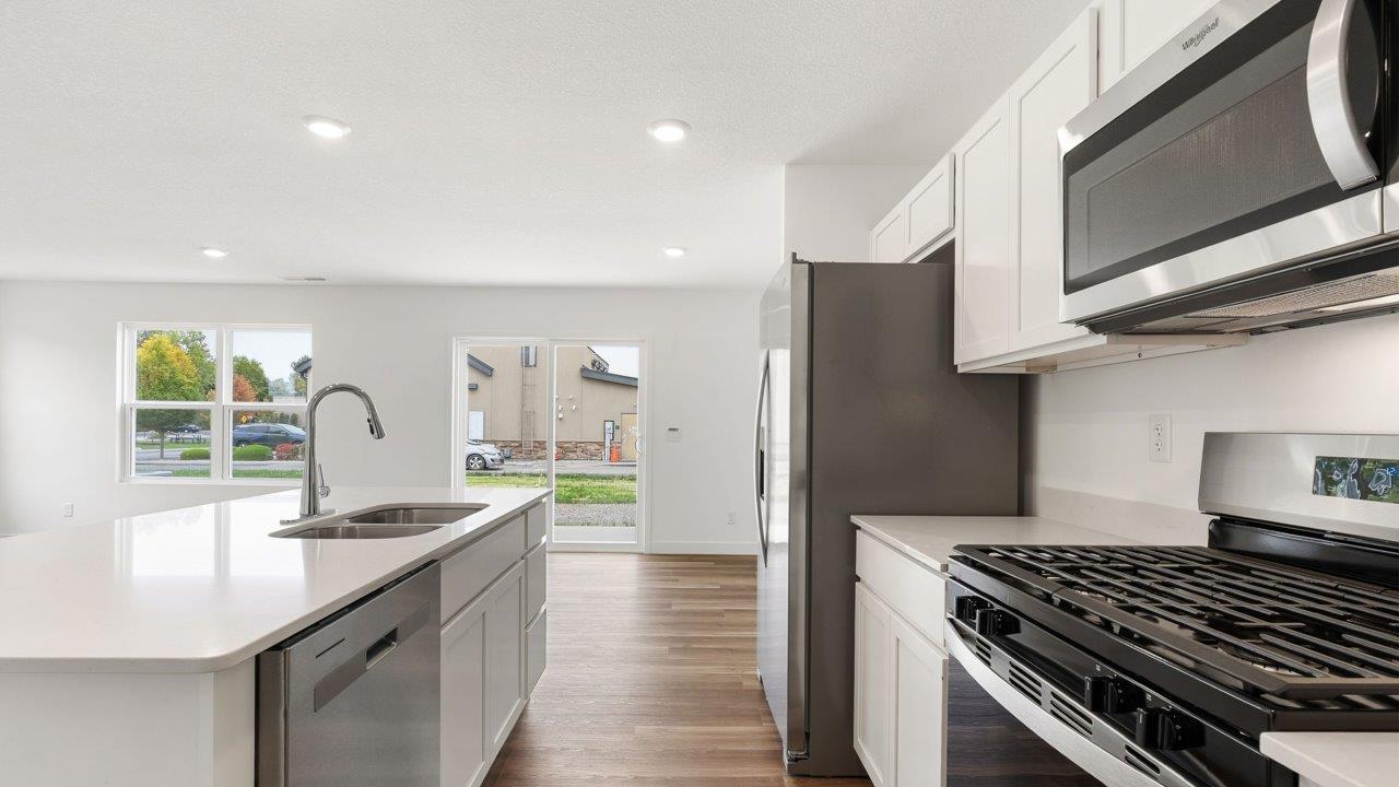 whispering pines portsmouth - kitchen with white cabinets, stainless steel appliances, quartz countertops, center island, and pantry