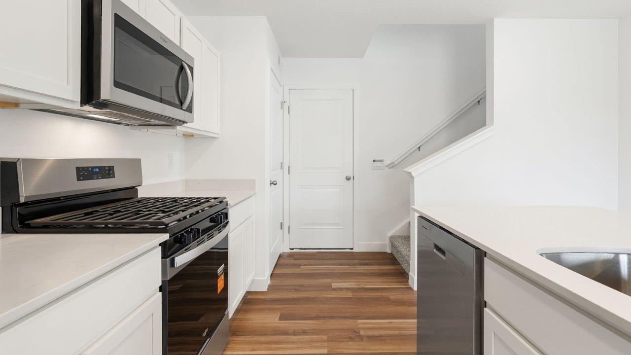 whispering pines portsmouth - kitchen with white cabinets, stainless steel appliances, quartz countertops, center island, and pantry