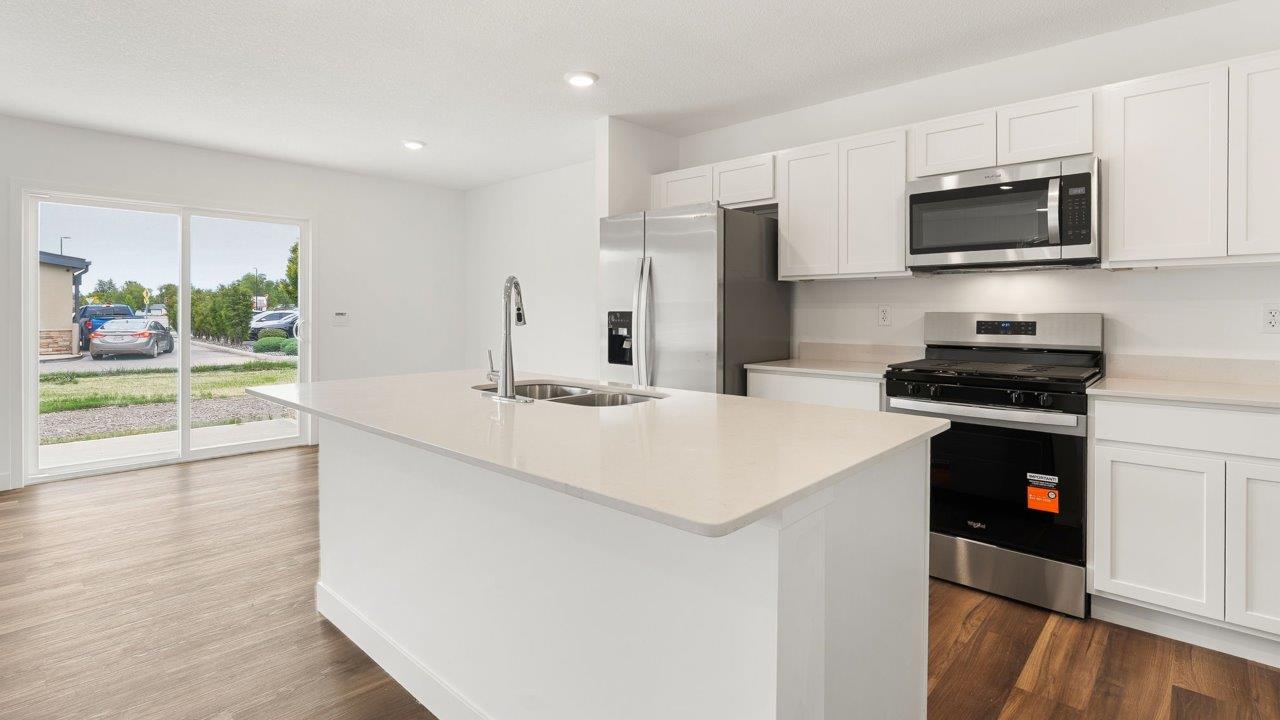 whispering pines portsmouth - kitchen with white cabinets, stainless steel appliances, quartz countertops, center island, and pantry