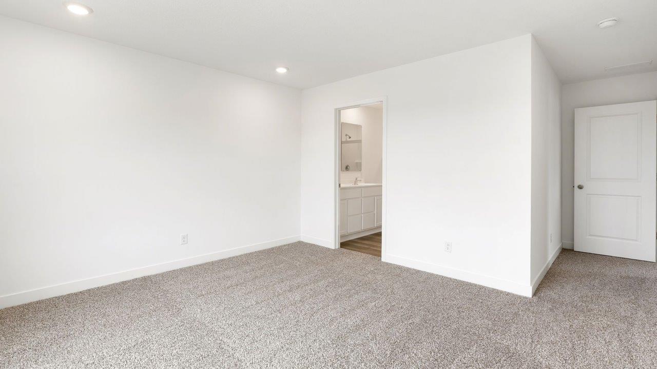 whispering pines portsmouth - primary bedroom with elk beige carpet flooring, 2 windows, white walls, and ensuite bathroom and walk in closet