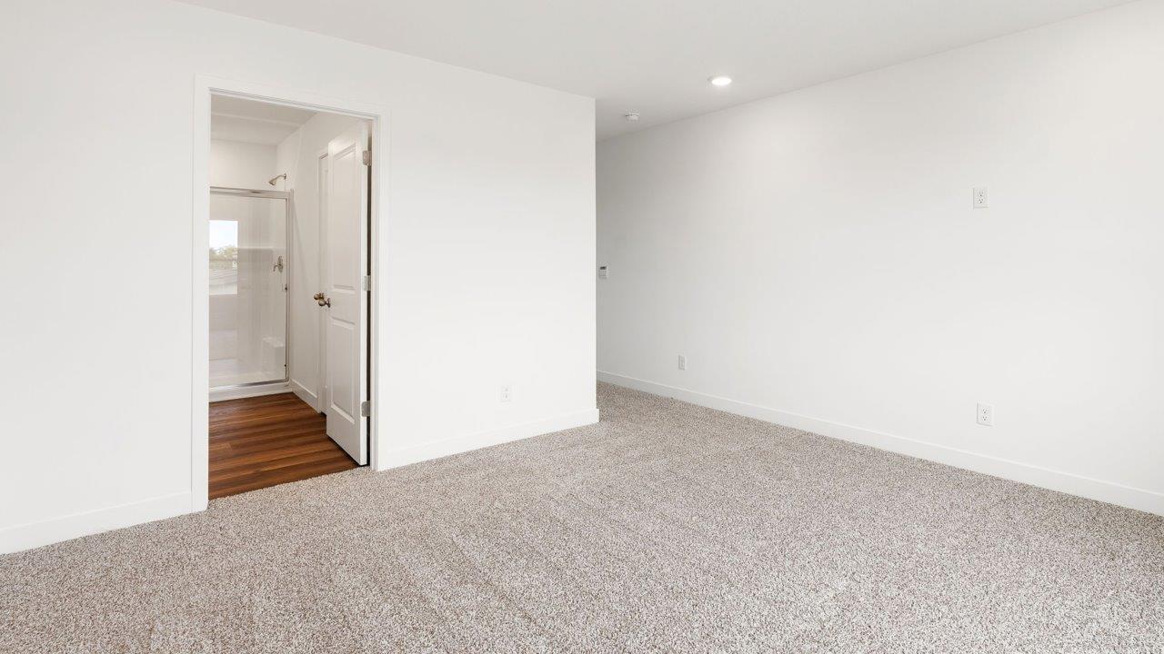 whispering pines portsmouth - primary bedroom with elk beige carpet flooring, 2 windows, white walls, and ensuite bathroom and walk in closet
