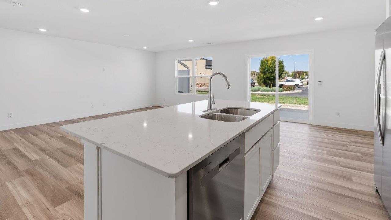 whispering pines portsmouth kitchen with white shaker cabinets, quartz countertops, stainless steel appliances, pantry, moahwk lvp flooring, white walls, and center island with room for bar seating